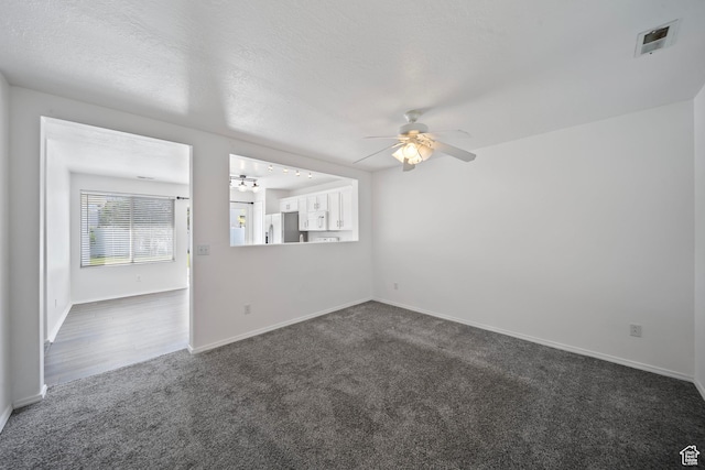 empty room with baseboards, a ceiling fan, dark colored carpet, and visible vents