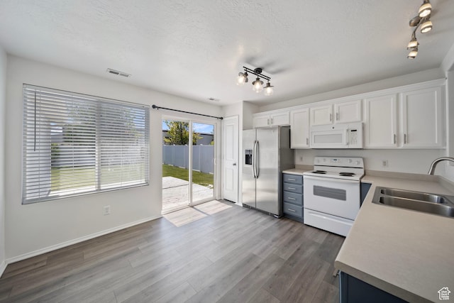 kitchen featuring a sink, white appliances, a textured ceiling, rail lighting, and white cabinetry