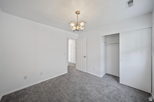 unfurnished bedroom featuring visible vents, baseboards, a closet, an inviting chandelier, and carpet flooring