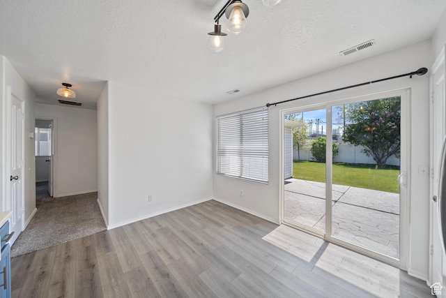 spare room with baseboards, a textured ceiling, visible vents, and wood finished floors