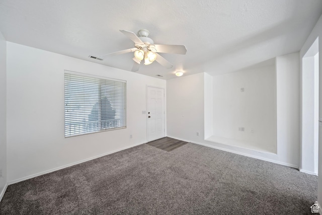 empty room featuring baseboards, ceiling fan, dark colored carpet, and visible vents