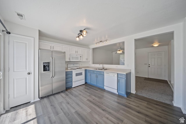 kitchen featuring blue cabinetry, light wood-type flooring, a sink, light countertops, and white appliances