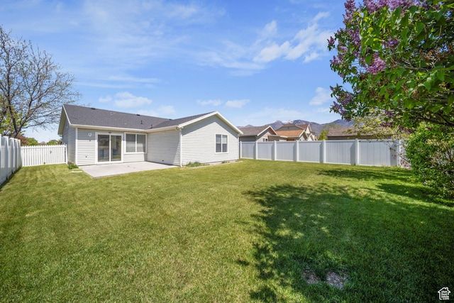 rear view of house with a lawn, a fenced backyard, and a patio area