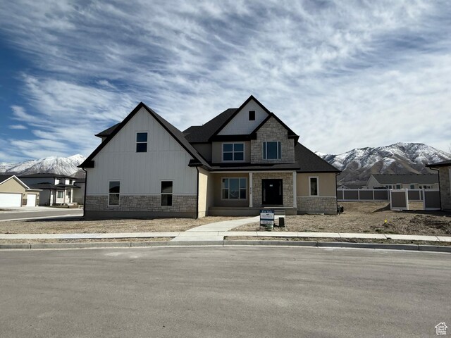 view of front of property with stone siding, a mountain view, and fence