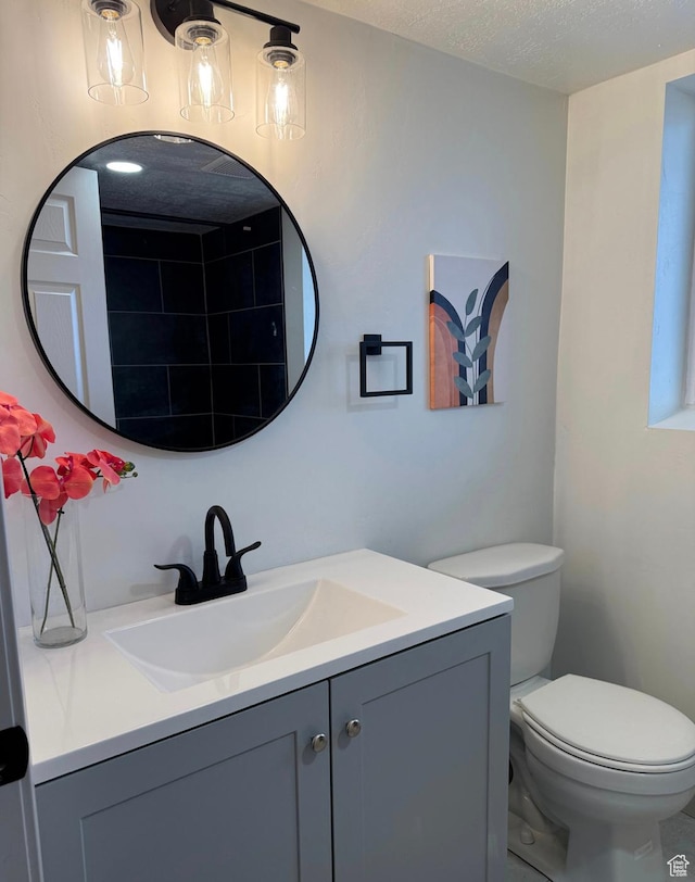 bathroom featuring toilet, vanity, and a textured ceiling