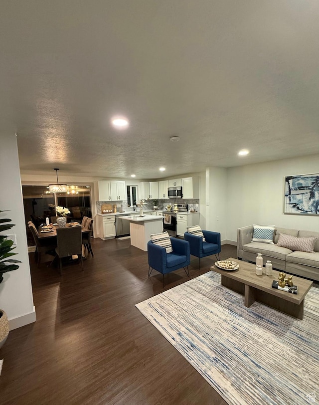 living area with baseboards, dark wood-type flooring, and recessed lighting