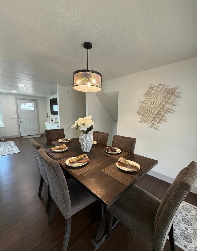 dining space featuring dark wood finished floors, a textured ceiling, and baseboards