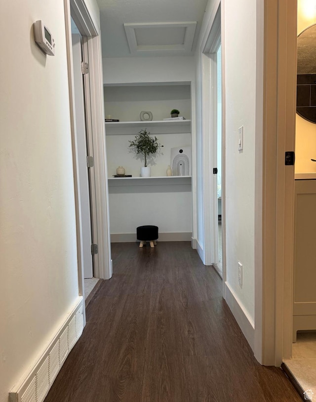 hall featuring dark wood-style floors, attic access, visible vents, and baseboards