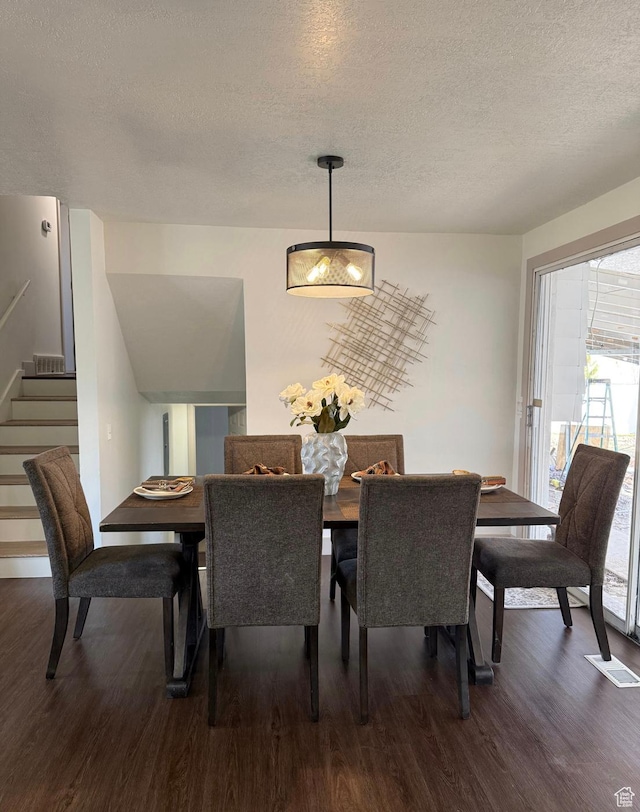 dining space featuring stairs, dark wood-style flooring, a textured ceiling, and visible vents