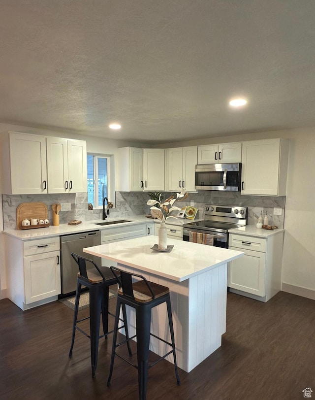 kitchen with white cabinets, stainless steel appliances, light countertops, and a center island