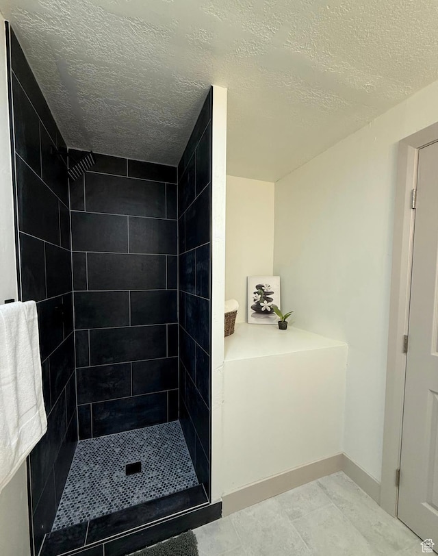 bathroom featuring a textured ceiling, a stall shower, and baseboards
