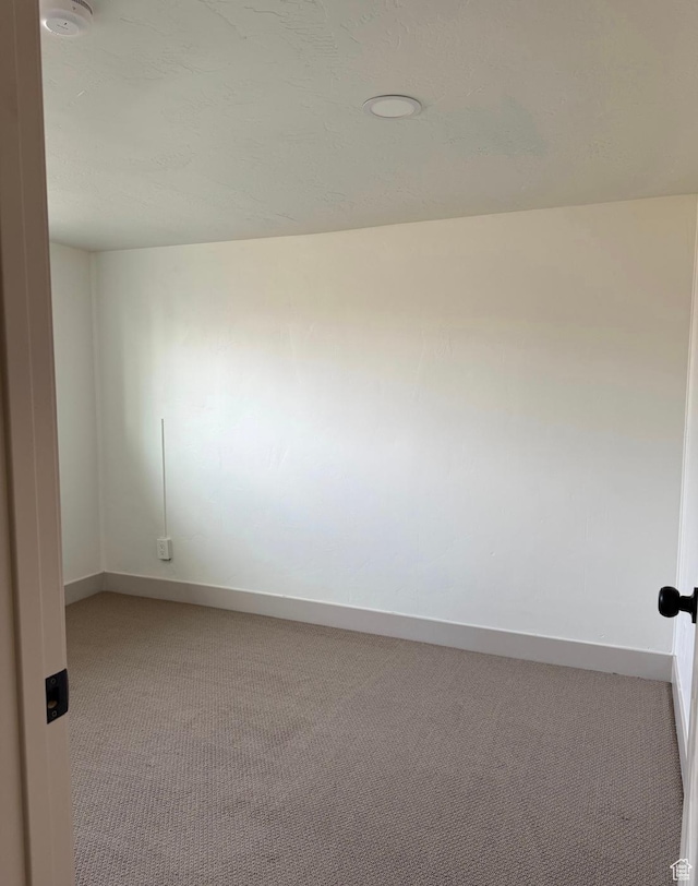 empty room featuring baseboards and light colored carpet