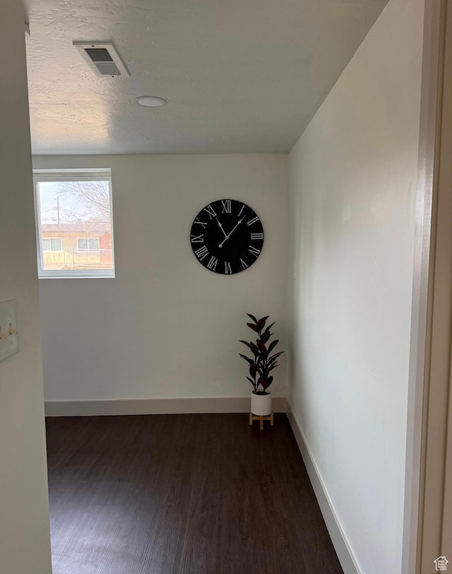 spare room with visible vents, baseboards, dark wood finished floors, and a textured ceiling