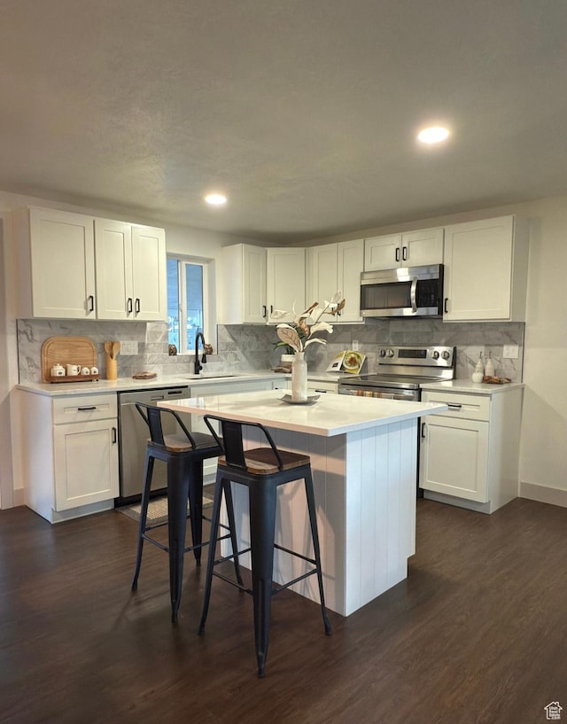kitchen with a center island, dark wood-style flooring, light countertops, appliances with stainless steel finishes, and white cabinetry