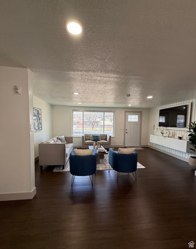 living room featuring dark wood-style floors, a textured ceiling, and baseboards
