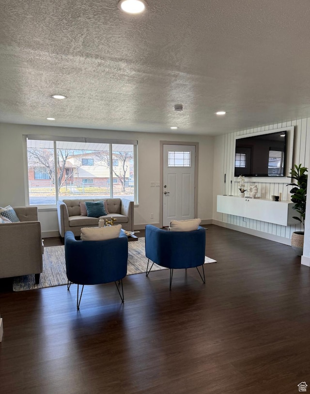 living room featuring a textured ceiling, recessed lighting, dark wood finished floors, and baseboards