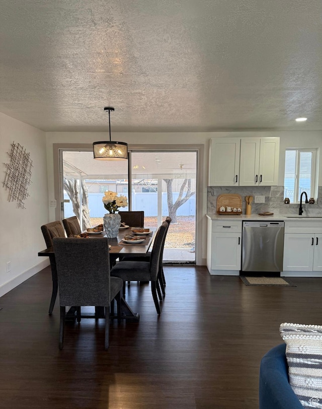 dining area featuring dark wood-style floors, a healthy amount of sunlight, a textured ceiling, and baseboards