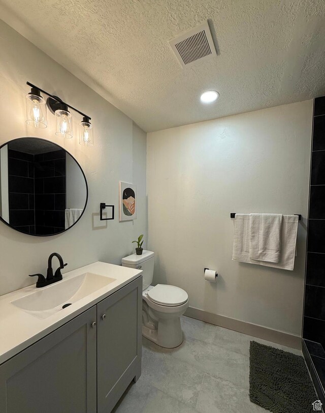 full bath with baseboards, visible vents, toilet, a textured ceiling, and vanity