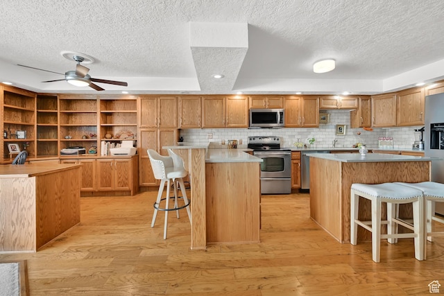 kitchen with appliances with stainless steel finishes, open shelves, a kitchen breakfast bar, a textured ceiling, and a kitchen island