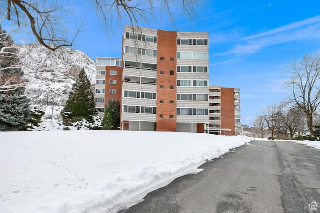 snow covered property with a view of apartment building / complex