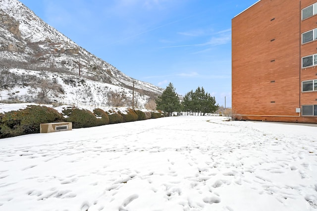 yard covered in snow featuring a mountain view