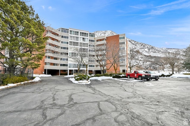 snow covered building with a mountain view and a view of apartment building / complex
