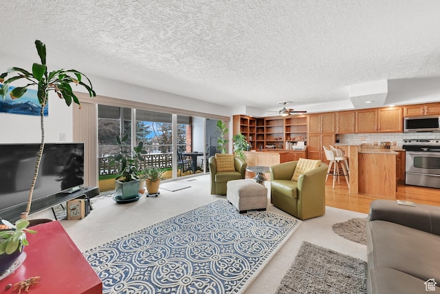 living area with ceiling fan and a textured ceiling