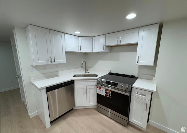 kitchen featuring stainless steel appliances, light countertops, light wood-style flooring, white cabinets, and a sink