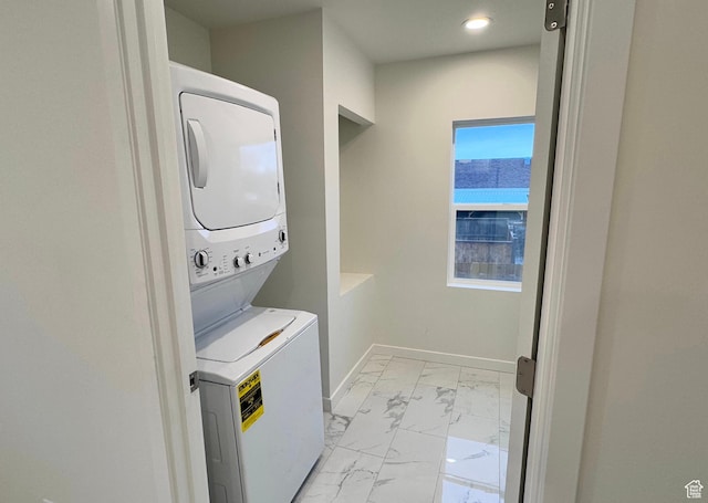 laundry room featuring marble finish floor, stacked washer and dryer, laundry area, and baseboards
