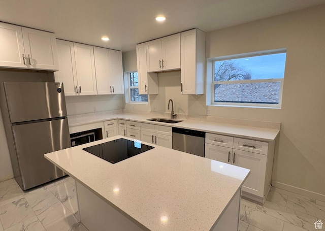 kitchen with marble finish floor, white cabinetry, stainless steel appliances, and a sink