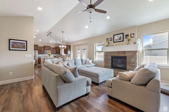 living area featuring dark wood-style floors, vaulted ceiling, a stone fireplace, and baseboards