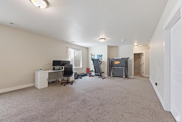 office space featuring light carpet, baseboards, visible vents, and a textured ceiling