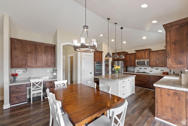 kitchen featuring appliances with stainless steel finishes, a center island, pendant lighting, and light stone counters