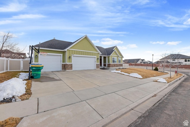 view of front facade featuring concrete driveway, stone siding, an attached garage, fence, and board and batten siding