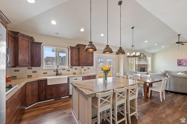 kitchen with a kitchen island, a kitchen breakfast bar, open floor plan, a sink, and stainless steel dishwasher