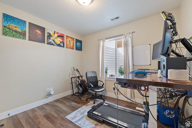 exercise area featuring baseboards, a textured ceiling, visible vents, and wood finished floors