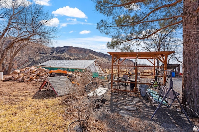 view of yard featuring a greenhouse, a mountain view, and an outdoor structure