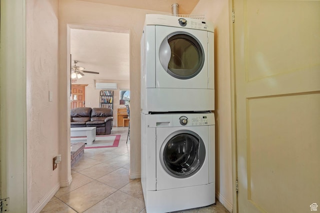 clothes washing area featuring laundry area, a wall unit AC, ceiling fan, stacked washing maching and dryer, and light tile patterned flooring