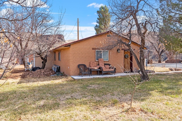 back of house featuring brick siding, a patio, and a yard
