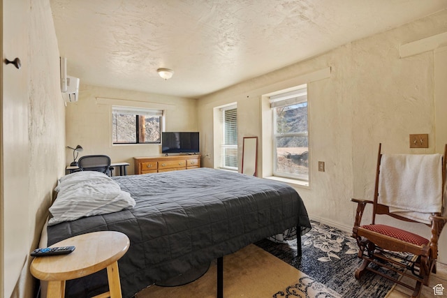 bedroom featuring multiple windows, baseboards, and a textured wall