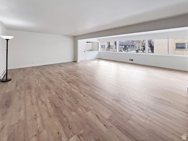 unfurnished living room with baseboards and light wood-style floors