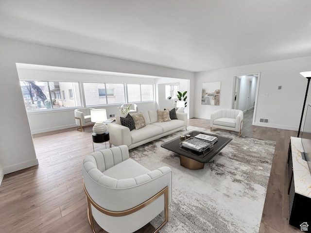 living area with a healthy amount of sunlight, light wood-type flooring, visible vents, and baseboards