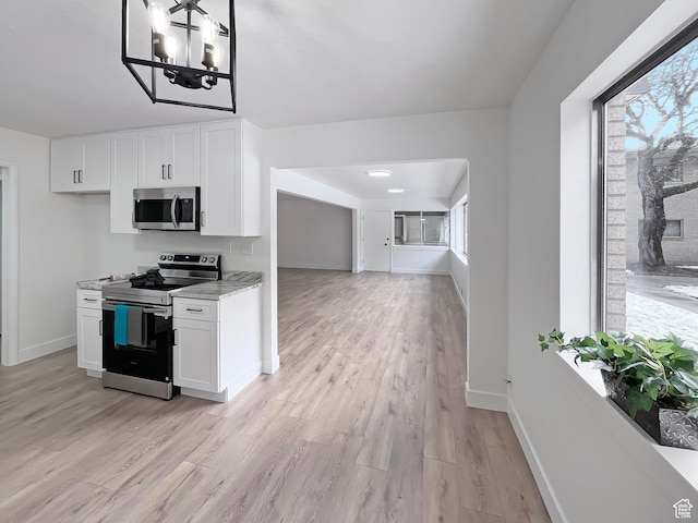 kitchen with light wood-type flooring, baseboards, white cabinetry, and stainless steel appliances