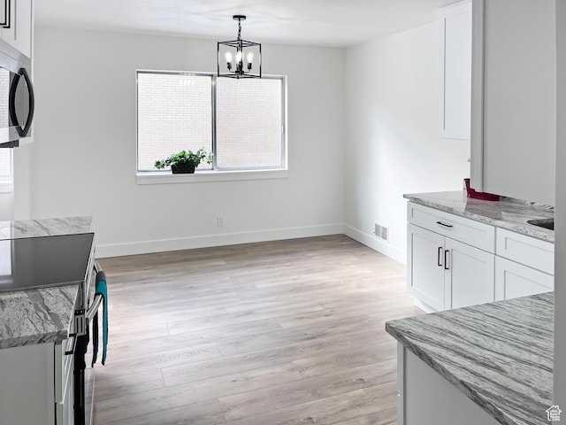 dining room with a notable chandelier, light wood-style flooring, visible vents, and baseboards