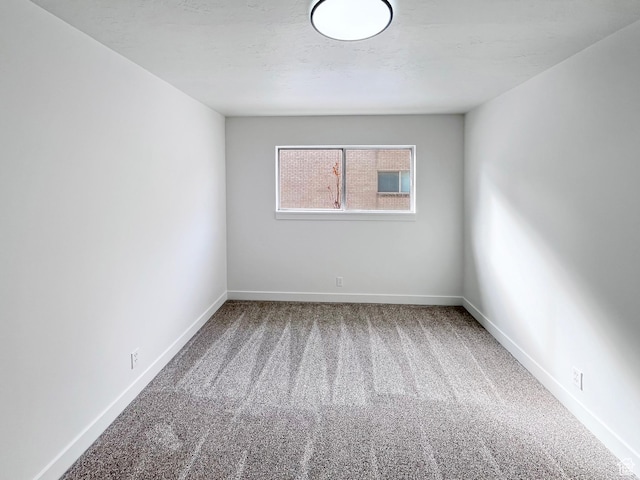 spare room with carpet, a textured ceiling, and baseboards