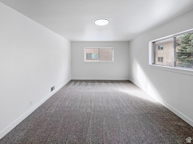 carpeted empty room featuring visible vents and baseboards