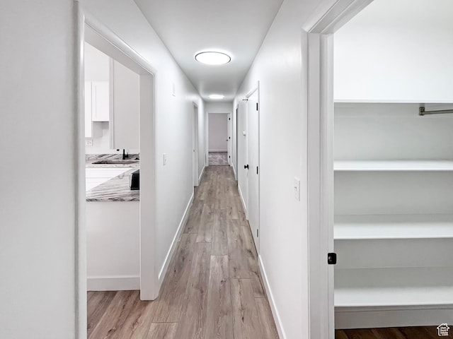 hallway featuring baseboards and light wood finished floors