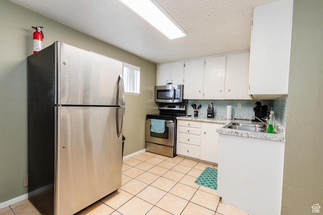 750 N 100 W, Logan, UT 84321 - kitchen featuring stainless steel appliances, a sink, white cabinets, light tile patterned floors, and backsplash