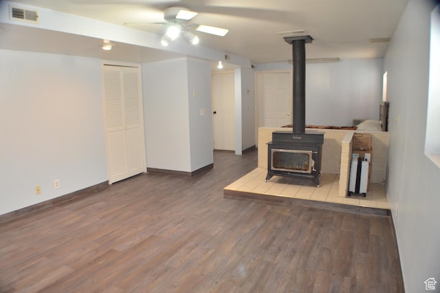5444 W Bailiff Dr S, Kearns, UT 84118 - unfurnished living room featuring a wood stove, baseboards, visible vents, ceiling fan, and wood finished floors