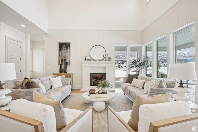 living room featuring a towering ceiling, a fireplace, and wood finished floors